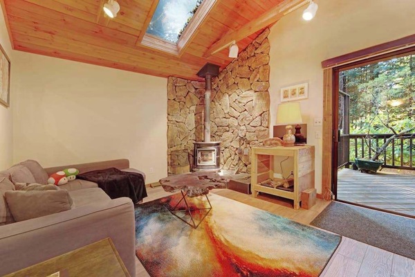 Cozy up by your wood-burning fireplace beneath soaring vaulted ceilings and a skylight that fills this redwood retreat with natural light.