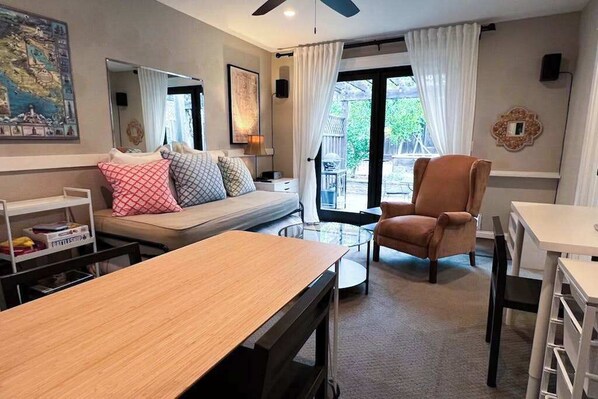 A living room with a sofa, armchair, coffee table, and a dining table.