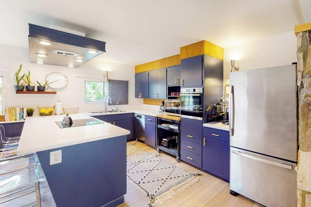 Une cuisine moderne dotée d’un îlot central, d’appareils électroménagers intégrés et d’un mur d’accent en pierre.