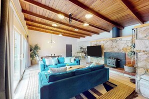 A spacious living room with a large blue sofa, a stone fireplace, and a television.