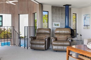 A modern living room with two leather recliners, a wooden coffee table, and a blue chimney. - Bodega Bay 3BR ocean-view home with game room and two king beds (Bodega Bay)