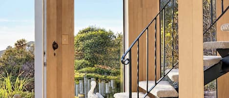 A spacious interior with wooden walls, a staircase with cushioned steps, and large windows offering views of the outdoors.