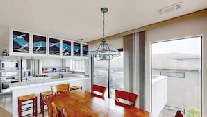 Una cucina moderna con mobili bianchi, un'area pranzo con tavolo e sedie in legno e un'ampia finestra con vista.