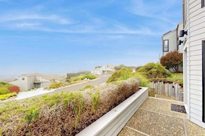 A residential property with a balcony overlooking a street and a clear sky. - Bodega Bay 3BR ocean-view home with game room & two king suites (Bodega Bay)