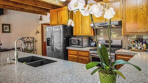 Una cucina con mobili in legno, un frigorifero in acciaio inossidabile, un forno a microonde e un lavello.