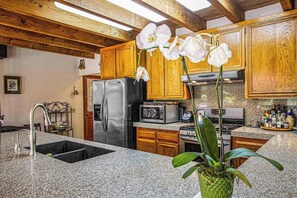 A kitchen with wooden cabinets, a stainless steel refrigerator, a microwave, and a sink. - Cazadero 4BR mountain cabin with hot tub in the redwoods — dog friendly (Cazadero)