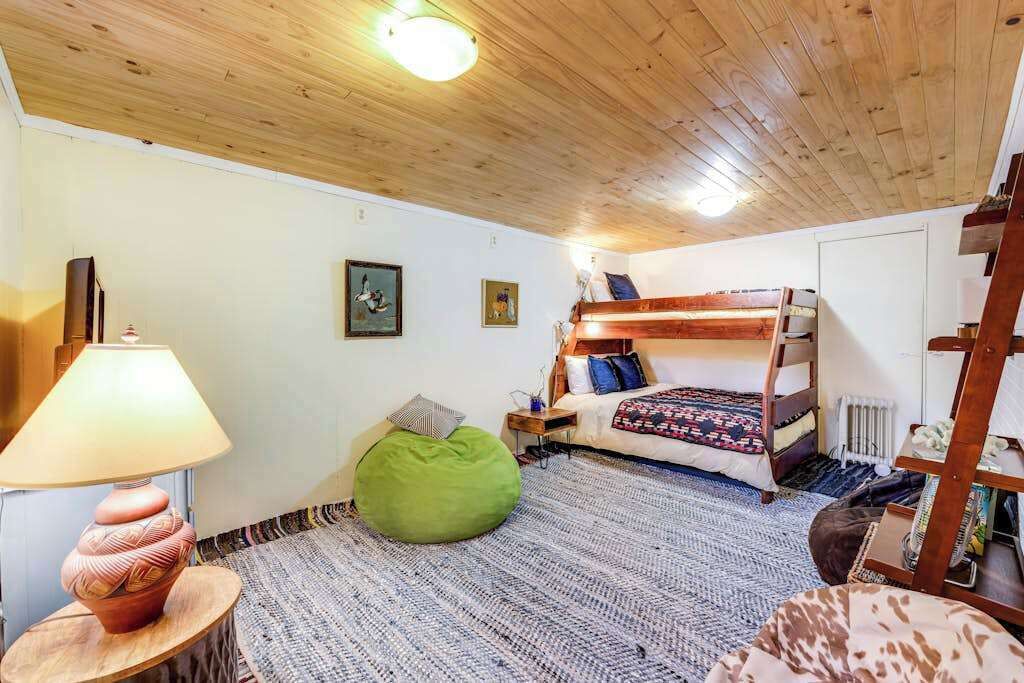 A room with a bunk bed, a green bean bag, a lamp, and a radiator.