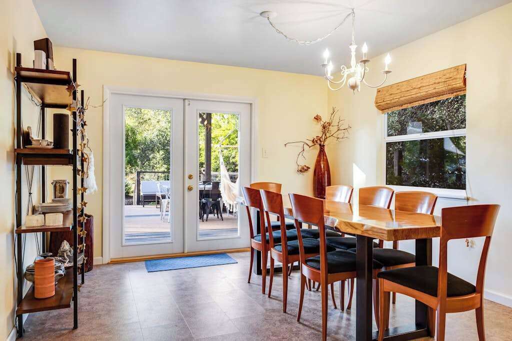 A dining area with a table and chairs, a chandelier, and a bookshelf.