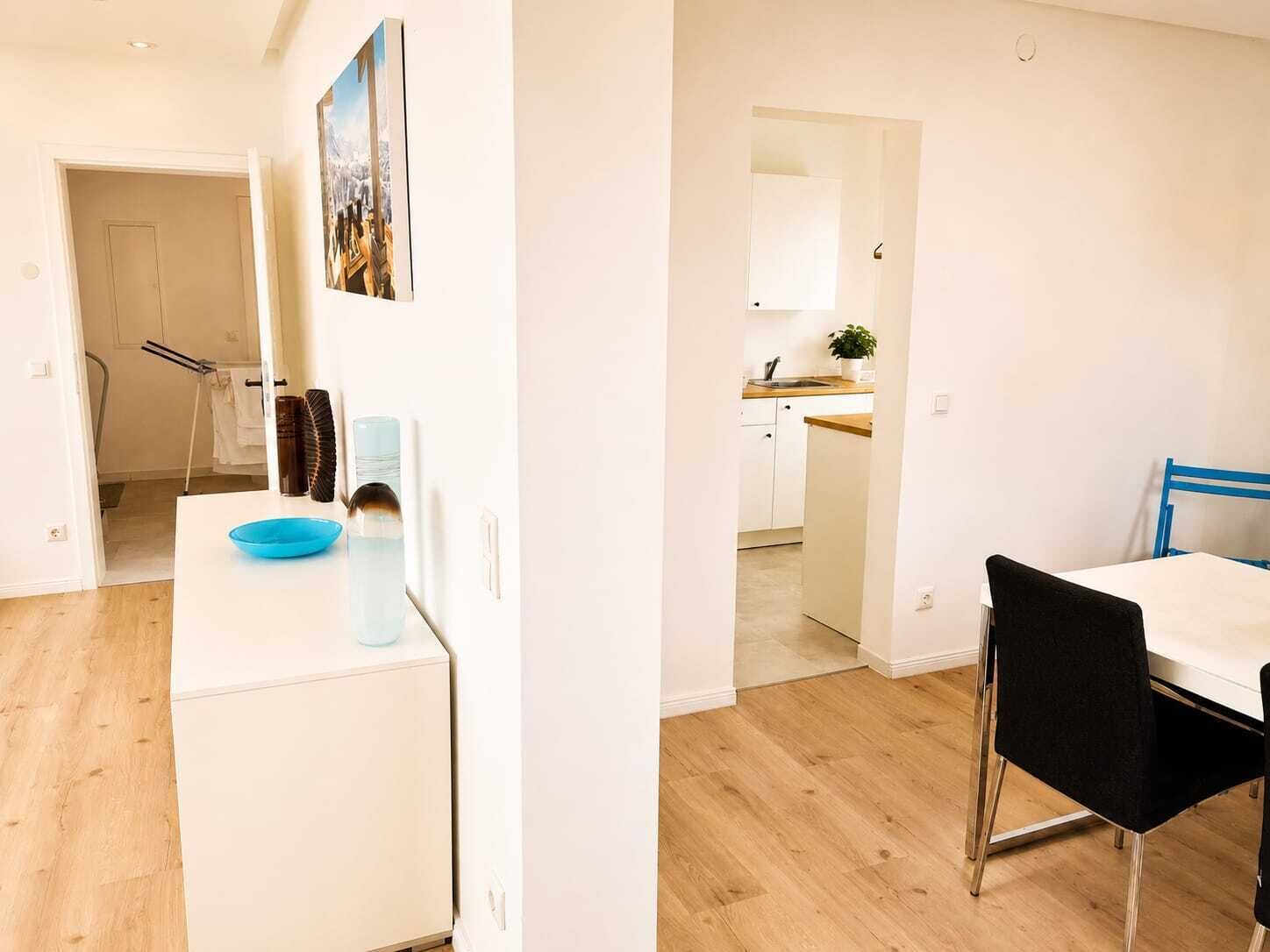 A modern apartment with a kitchen, dining area, and a bathroom visible through an open door.