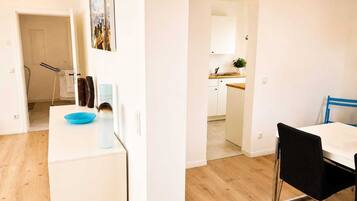 A modern apartment with a kitchen, dining area, and a bathroom visible through an open door.