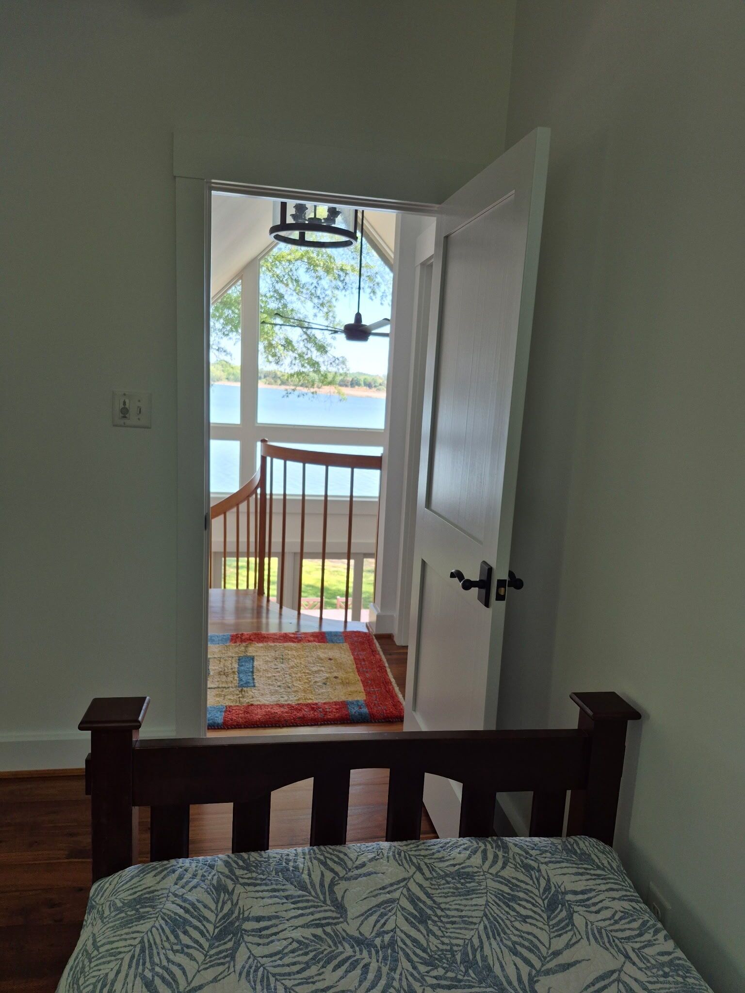 Ein Schlafzimmer mit einem Bett, einer Tür, die auf einen Balkon führt, und Blick auf ein Gewässer.