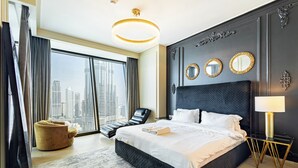 Una habitación de hotel moderna con una cama grande, vistas a la ciudad, un sillón de descanso y un candelabro.
