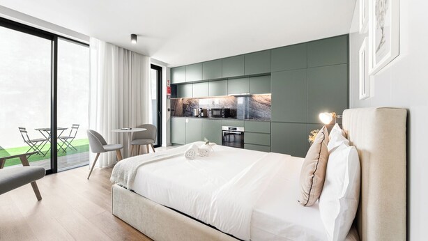 Ein modernes Hotelzimmer mit einem großen Bett, einem Essbereich und einer Küche.