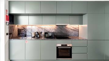 Une cuisine moderne dotée d’un pare-feu en marbre, d’appareils électroménagers intégrés et d’un design minimaliste.
