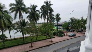 A street view with palm trees, a river, and a bridge in the background. - July Hotel Quang Binh (Dong Hoi)