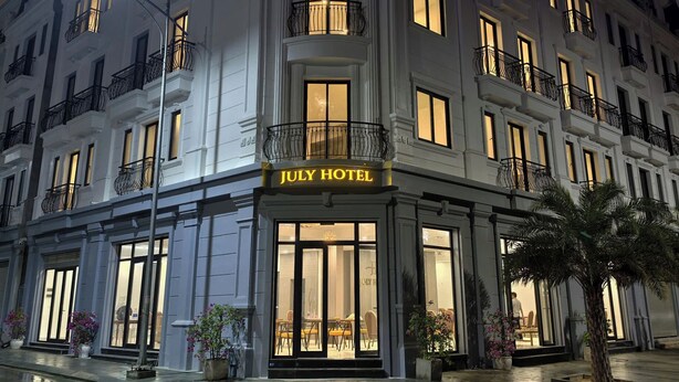 A hotel with a classic facade, large windows, and a balcony with railings. - July Hotel Quang Binh (Dong Hoi)