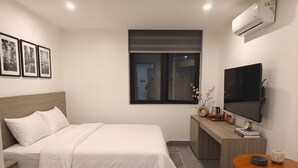 A neatly arranged hotel room with a bed, a desk, a television, and a window. - July Hotel Quang Binh (Dong Hoi)