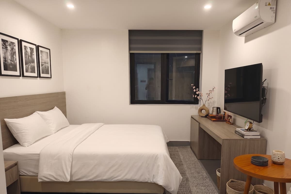 Habitación de hotel ordenada con cama, escritorio, televisor y ventana.