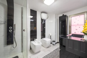 Uma casa de banho moderna com cabine de duche em vidro, um bidé, sanita e lavatório com painel decorativo rosa.
