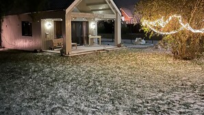 A house with a covered porch, a small garden, and a tree with lights. - Tiny House Pusteblume with Private Terrace and Wi-Fi (Wesseln)