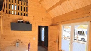 A wooden interior with a table and chairs, a door leading outside, and a window with blinds. - Tiny House Pusteblume with Private Terrace and Wi-Fi (Wesseln)