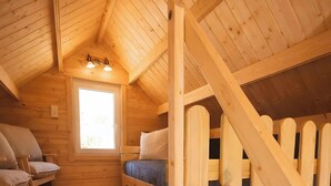 A wooden cabin with a loft bedroom, a small window, and a staircase. - Tiny House Pusteblume with Private Terrace and Wi-Fi (Wesseln)