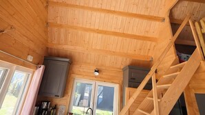 A wooden interior with a kitchen area, a staircase, and a view through the windows. - Tiny House Pusteblume with Private Terrace and Wi-Fi (Wesseln)