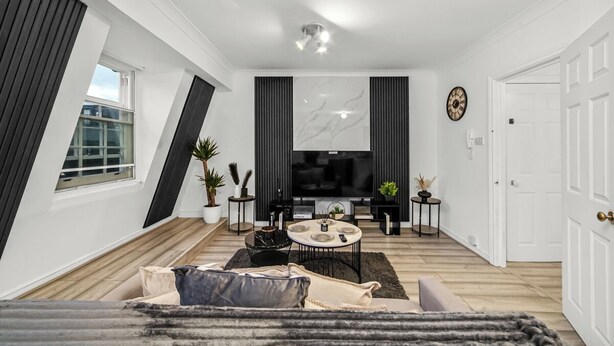 Ein modernes Wohnzimmer mit Flachbildfernseher, Essbereich und großem Fenster.
