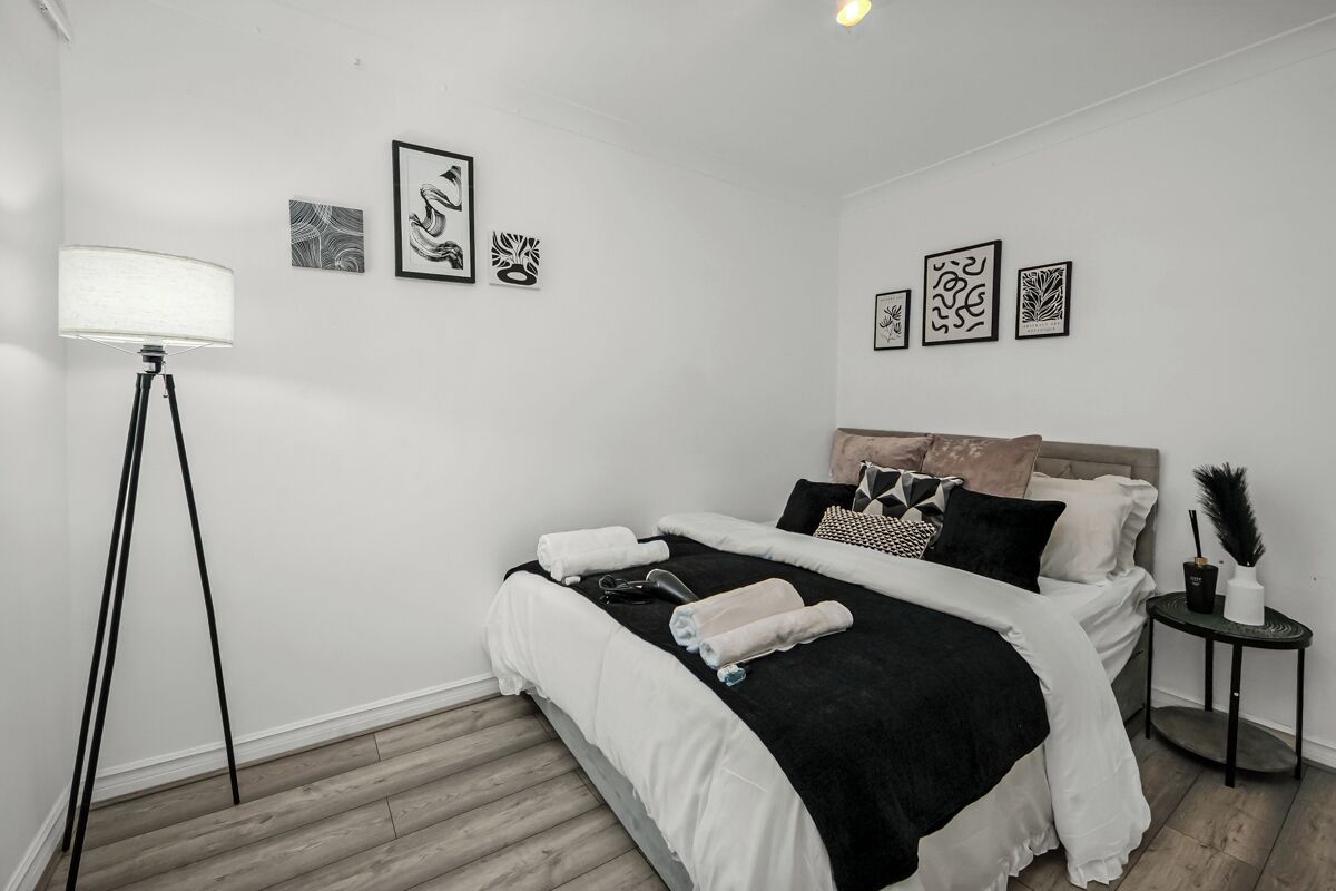 Ein Schlafzimmer mit Bett, Nachttisch, Lampe und Wandbild.