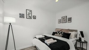 Ein Schlafzimmer mit Bett, Nachttisch, Lampe und Wandbild.