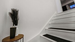 Eine Treppe mit weißen Wänden und einem Holznachttisch mit einer Vase.