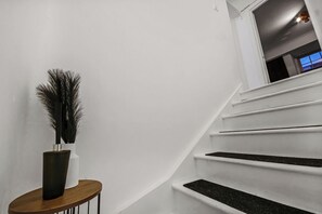 A staircase with white walls and a wooden side table with a vase. - Entire Apartment in the Heart of Soho London// Best location in London (London)
