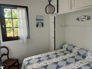 A bedroom with a bed, a chair, a window with curtains, a door, and a wall-mounted sign. - Quiet house near the ocean (Biscarrosse)