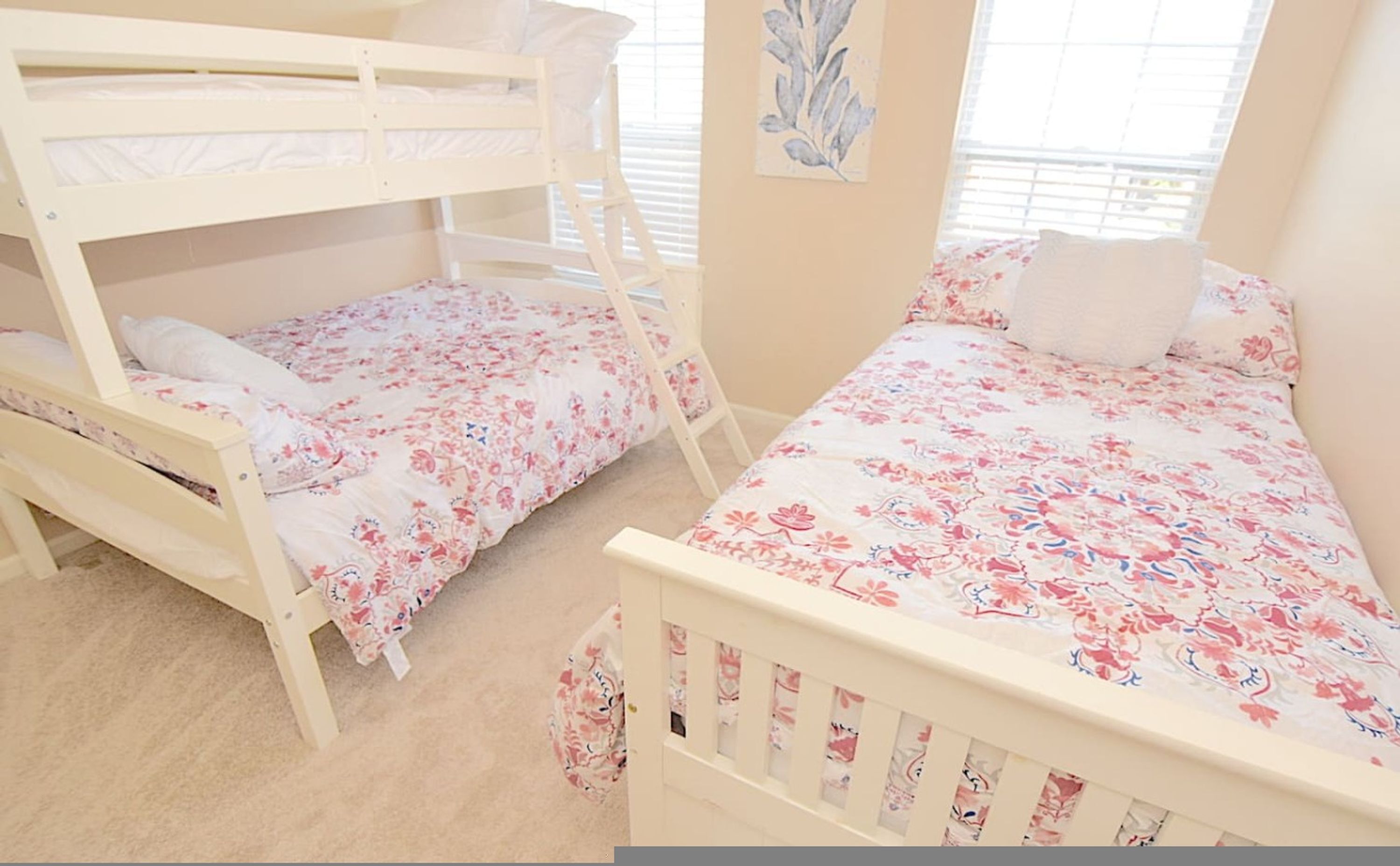 A room with two bunk beds, a ladder, and a floral-patterned bedspread.