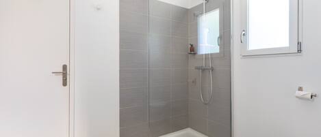 A modern shower area with a glass door, a handheld showerhead, and a wall-mounted towel rack.