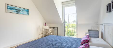 Une chambre avec un grand lit, un bureau et une chaise, une fenêtre avec vue et un luminaire au plafond.