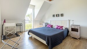 A bedroom with a bed, a chair, a nightstand, a lamp, and a window.