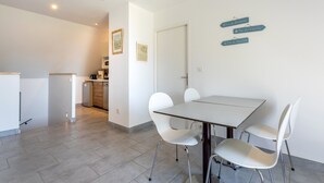 A modern kitchen with white cabinetry, a dining table with four chairs, and directional signs on the wall.