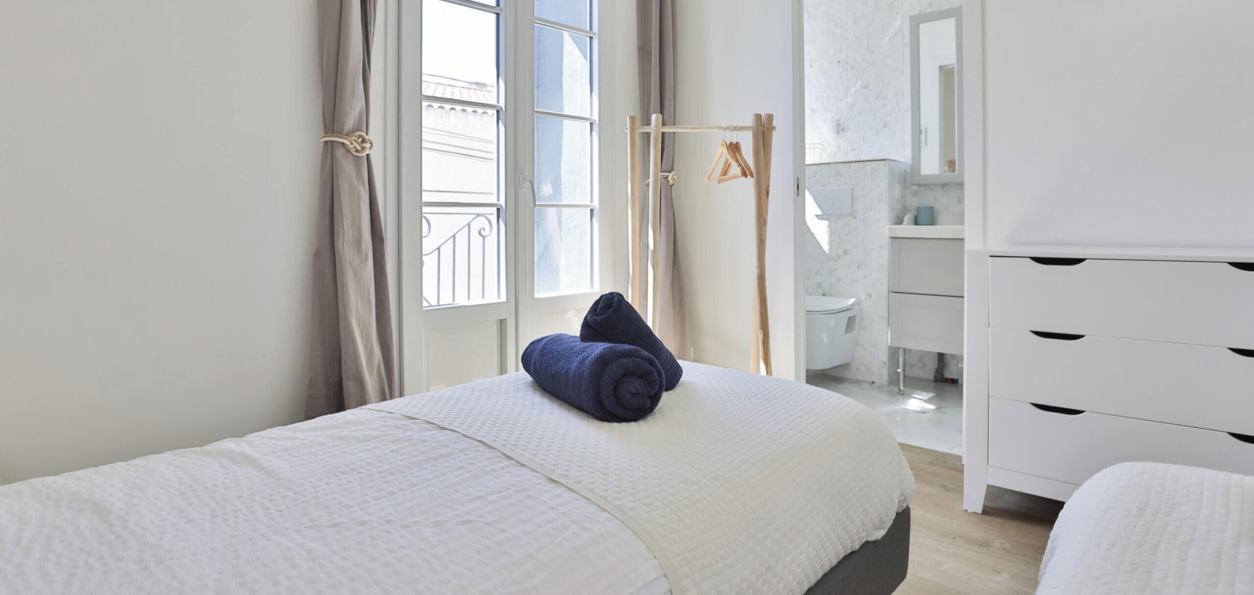 Une chambre d’hôtel avec un lit, une armoire, une fenêtre avec des rideaux et une vue sur l’extérieur.