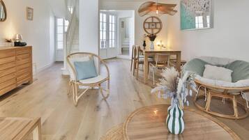 Un salon moderne avec un téléviseur, des meubles en bois, un coin repas et une grande fenêtre.