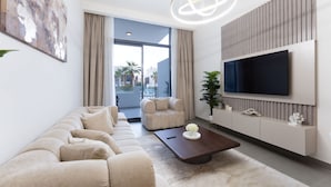Een moderne woonkamer met een bank, een salontafel, een televisie en een groot raam.