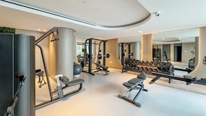 Een moderne sportschool met diverse trainingsapparaten, grote spiegels en een ruimtelijke, schone indeling.