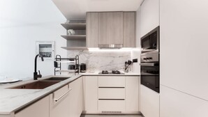 Een moderne keuken met een marmeren aanrecht, roestvrijstalen apparatuur en licht houten kastjes.