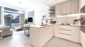 Een moderne keuken met witte kasten, een marmeren aanrecht en een ingebouwde oven.