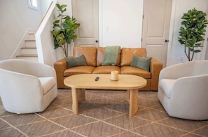 Un salon comprenant un canapé, deux fauteuils, une table basse et un tapis.