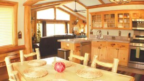 Un interior de madera con una mesa de comedor, sillas, una zona de cocina con armarios de madera y un horno grande.