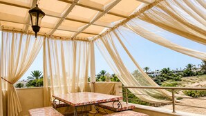Katettu ulkoalue, jossa on pöytä ja penkkejä, riippuvalaisin ja näkymä maisemaan.