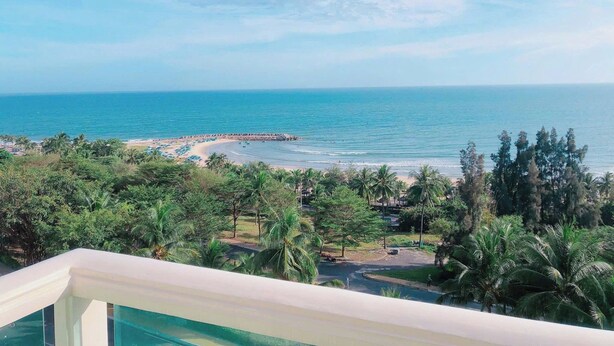 A coastal view with a beach, palm trees, and a clear sky. - Căn Hộ View Biển (Phú Thủy)
