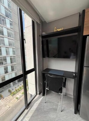 A modern room with a desk, chair, and a flat-screen TV mounted on the wall. - Usaquen Loft (Bogotá)