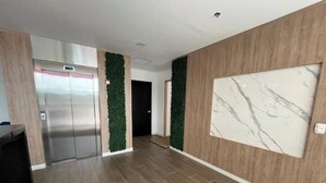 Un pasillo moderno con piso de madera, pared de mármol y panel de pared verde.
